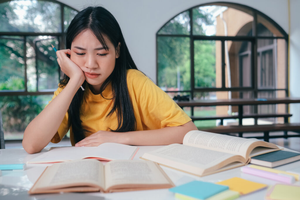 a photo of a frustrated student reviewing her O level chemistry study guide, seemingly wondering what makes her answer incorrect