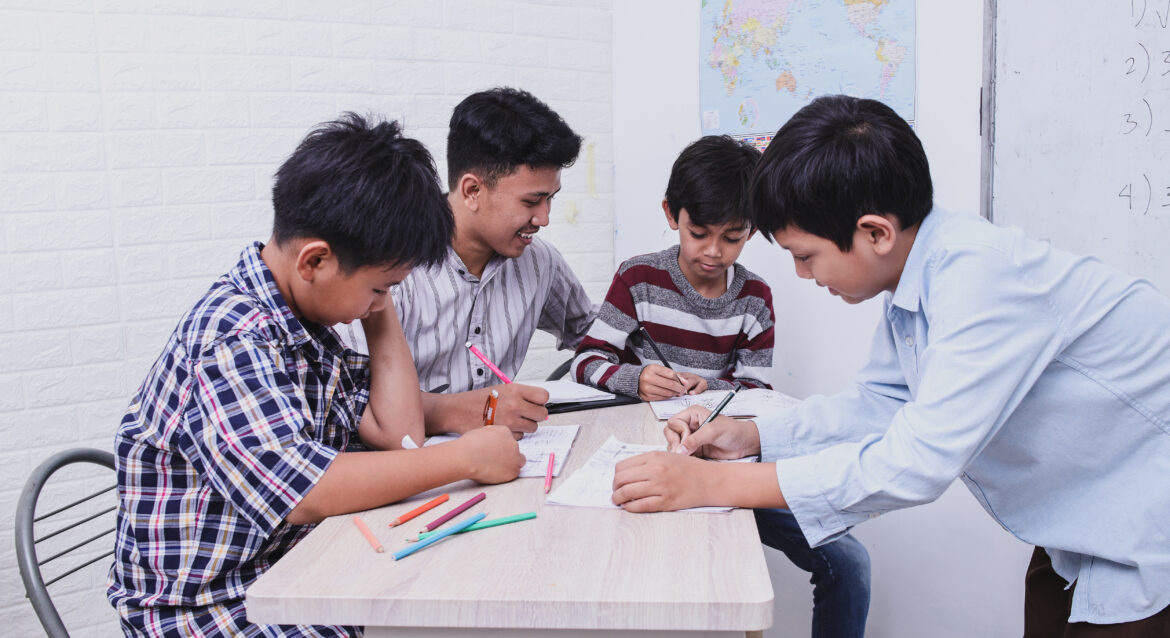 A group of students gathered around a work table working on how to solve PSLE problem sums