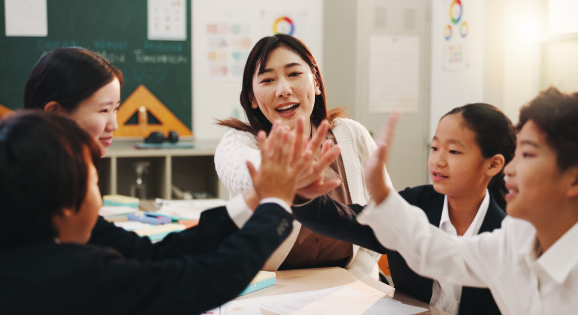 a small group teacher in a math tuition in Singapore with students giving high five to each other