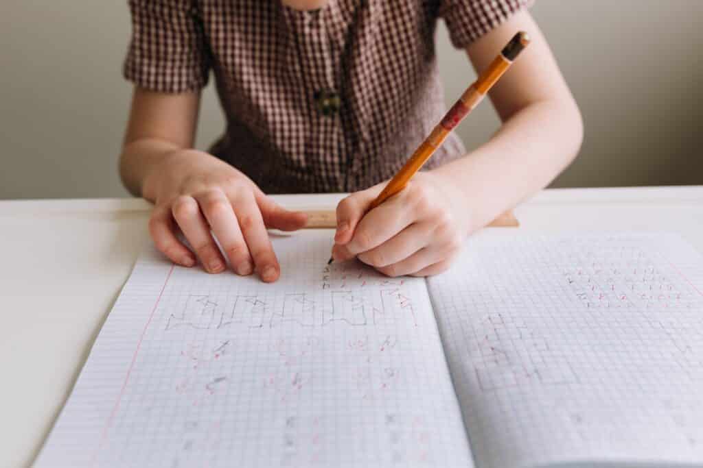 Child drawing a bar model to represent the relationships in a PSLE problem sum