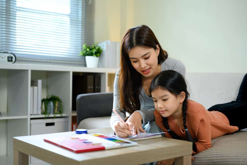 Parent reviewing a child's maths working together at home before PSLE