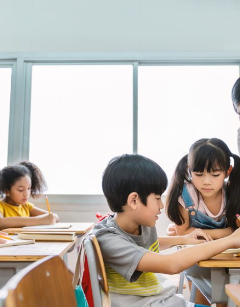 Pupil,Boy,Hi,Five,With,Asian,Teacher,In,Classroom,At